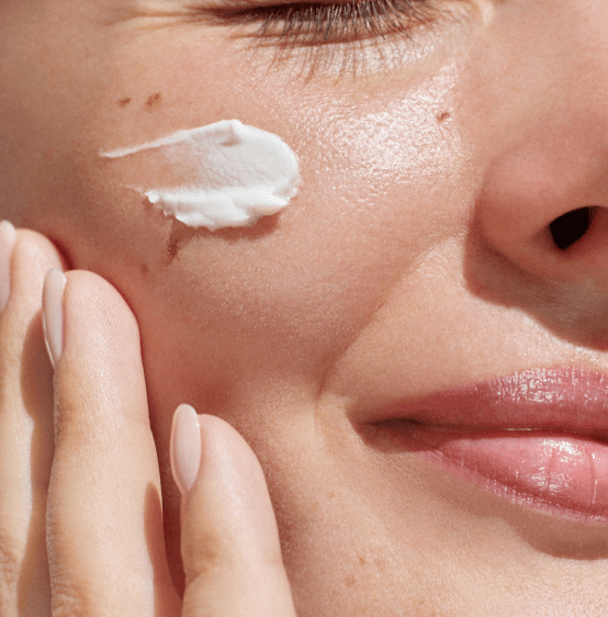 امرأة تستخدم منتجات العناية بالبشرة على وجهها لإضفاء لمسة من النعومة والاعتناء بالبشرة